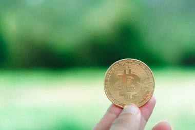 Elle metin koyabilirsiniz copyspace ile doğa arka plan ile kripto para birimi olarak Bitcoins bir sembol tutun.