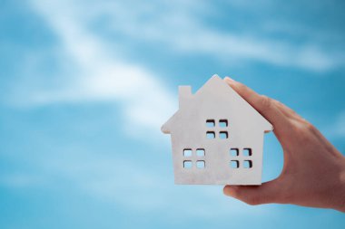 O kadının arka planında tuttuğu küçük bir evin maketi var. Rüya aile hayatı konsepti.