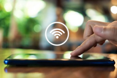 Açık alan arka planında wifi ikonu olan akıllı telefon kullanan bir kadın. İş iletişimi sosyal ağ kavramı.