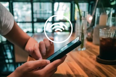 Kafe arka planında wifi ikonu olan akıllı telefon kullanan bir kadın. İş iletişimi sosyal ağ kavramı.