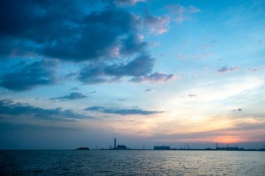 Günbatımı ya da gündoğumu gökyüzü ve sahil Endüstriyel Estate arka planı.