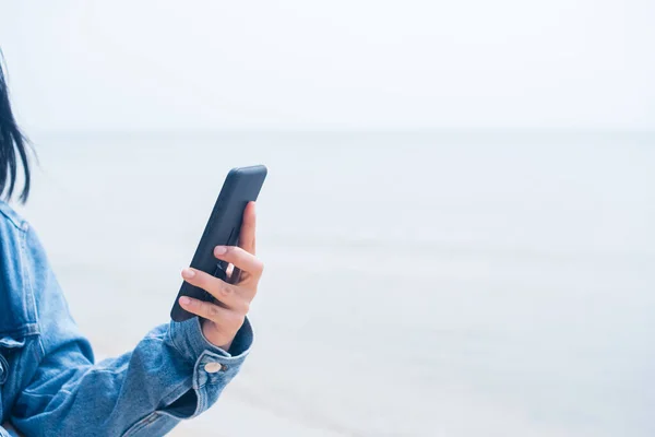 Woman using smartphone to do work business, social network, communication with beach outdoor background.