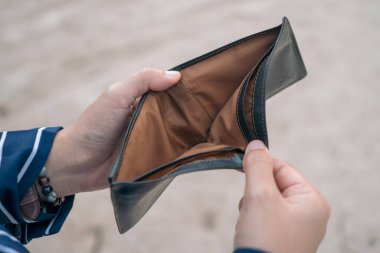 Kadın elinde boş bir çanta ve sikke tutuyor. Yani para sorunu ya da iflas etmiş işsiz, kredi kartı işsizliği ve borç konsepti yüzünden beş parasız..