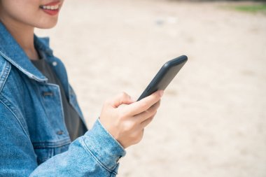 Akıllı telefonu iş yapmak için kullanan kadın, sosyal ağ, plaj arka planıyla iletişim..