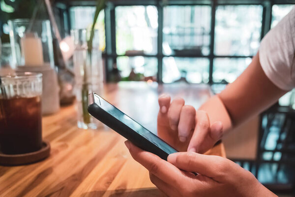 Woman feel happy and smile while using smartphone to do work business, social network, communication in public cafe work space area.