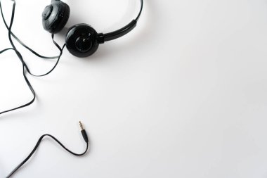 Beyaz ya da pastel renkli arka planda siyah kulaklıkların üst görüntüsü. Müzik konsepti.