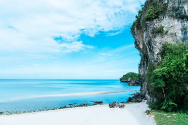 Tropikal doğa temiz plaj ve yaz aylarında kayalık mavi gökyüzü arka planıyla beyaz kum.