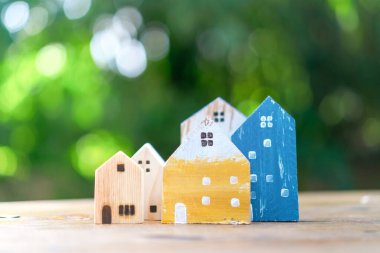 Küçük ev modelini yere ya da güneş ışığı yeşil bokeh arka planlı ahşap masaya kapattım. Deam 'in yaşam ve yatırım konsepti için kendine ait bir mülkü var..