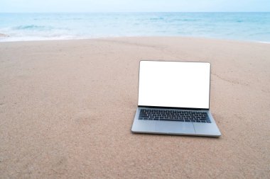 Yaz plajında beyaz ekranlı kumda dizüstü bilgisayar..