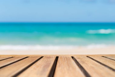 Ürününüzü göstermek için güzel plaj arka planına sahip eski ahşap masanın seçici odağı.