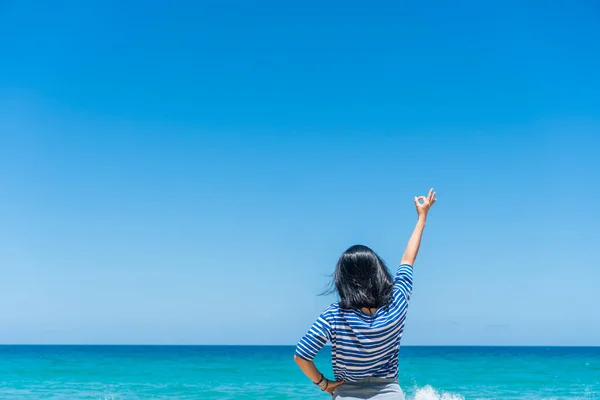 Woman rise hands up to sky freedom concept with blue sky and summer beach background.