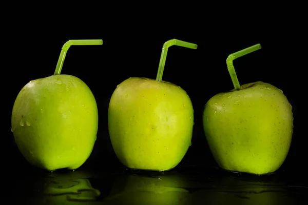 Green apples in water on a black background