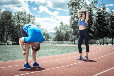 Genç Yetişkin fitness kaç egzersiz öncesi egzersizleri açık atletizm koşu parkuru alanına kadar germe Isınma yapıyor. Tonlu görüntü.