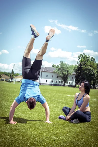 Genç adam ellerinde baş aşağı açık havada açık hava çim sahada ayakta yerleştirmek.