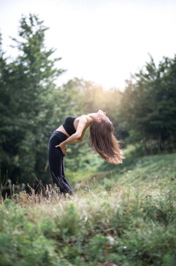 Sabah saatlerinde doğada germe egzersiz yaparak genç çekici kadın. Tonlu görüntü.