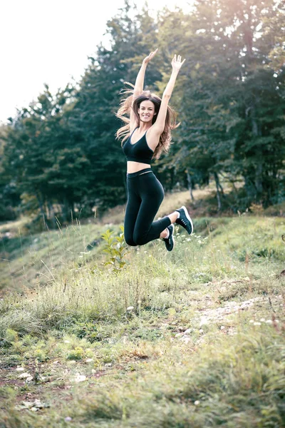 Young happy sport woman jumping high outdoor on meadow. Toned image.