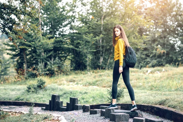 Genç esmer kadın sarı kapüşonlu Dağı trekking. Tonlu görüntü.
