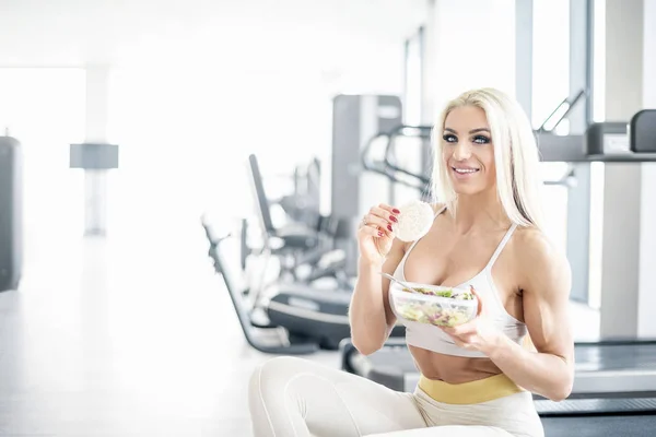 Blonde vrouw in sportschool gezond eten. — Stockfoto