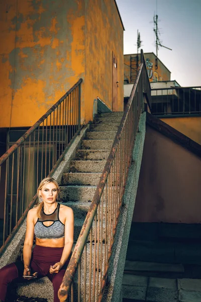 Fitness kadın çatıda merdivenlerden oturuyor — Stok fotoğraf