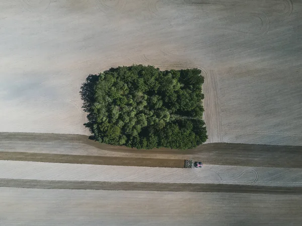 Luchtfoto van een landbouwtrekker in een veld tijdens het ploegen van land voor het verbouwen van voedsel. — Stockfoto