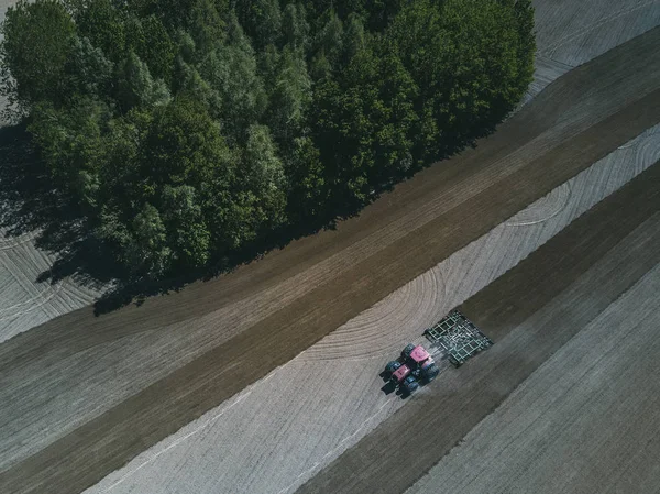 Luchtfoto van een landbouwtrekker in een veld tijdens het ploegen van land voor het verbouwen van voedsel. — Stockfoto