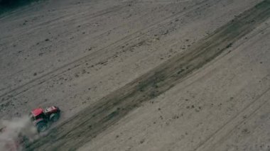 DRON AERİAL FOOTAJ. Traktör sabanı çekiyor, havaya toz fırlatıyor. Buğday tarlasında hasat makinesini birleştirin. Tarım sırasında ağır makineler, Belarus 'ta tarlalarda çalışmak
