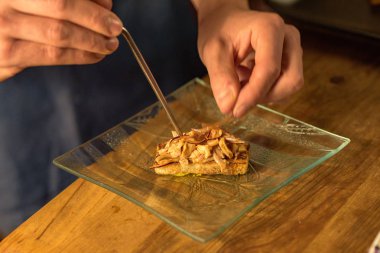 Chef cutting green onions on wooden board in dim light.