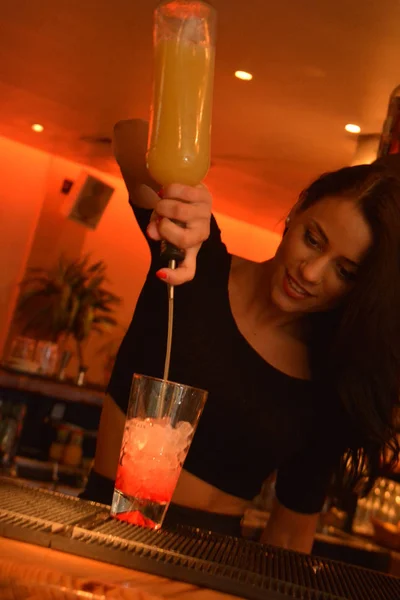 Ibiza, Spain : 2016 28 July: Young brunette girl bar tender serves drink at night in Ibiza.