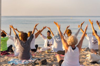 Altafulla, Tarragona, İspanya : 219 Ağustos 31 : Yoga eğitmeni Altafulla, Tarragona, İspanya plajda gün batımında bir grup oturumu lider