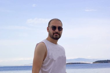 Sahilde güneş gözlüklü genç adam.