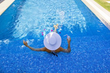  Havuzda dinlenen beyaz şapkalı genç bir kadın.