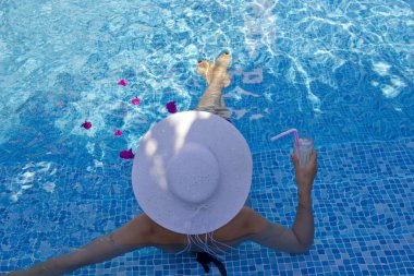  Havuzda dinlenen beyaz şapkalı genç bir kadın.