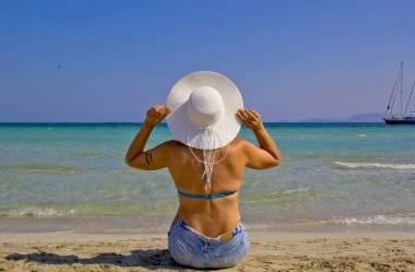 Kumsalda şapkalı güzel bir kadın.