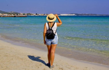 Kumsalda şapkalı güzel bir kadın.