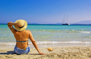 Kumsalda şapkalı güzel bir kadın.