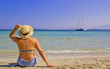 Kumsalda şapkalı güzel bir kadın.