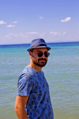 Sahilde güneş gözlüklü genç adam.