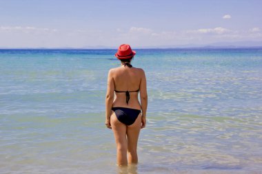 Kumsalda kırmızı şapkalı güzel bir kadın.