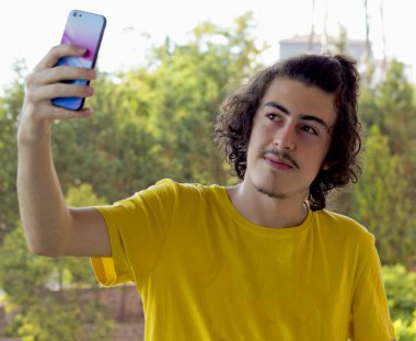 Mutlu genç adam cep telefonuyla selfie çekiyor.