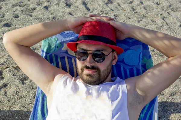 Kumsalda şapkalı yakışıklı bir genç.