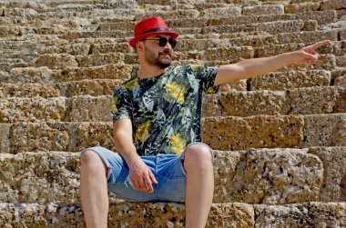 Efes antik şehrinde kırmızı şapkalı yakışıklı bir genç.