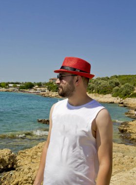 Kumsaldaki kırmızı şapkalı genç adam.