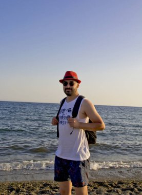 Kumsaldaki kırmızı şapkalı genç adam.