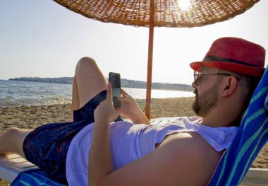 Kumsaldaki kırmızı şapkalı genç adam.