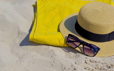 Güneş gözlüğü, havlu ve kumda şapka.