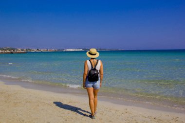 Kumsalda şapkalı güzel bir kadın.