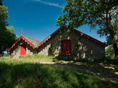 Ağaçların altında bir göl kenarında kırmızı kiriş mavi gökyüzü ile güneşli bir günde iki boathouses