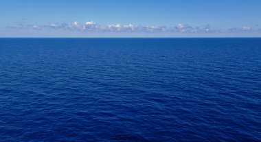 Bazı bulutlar ve ufukta ışık mavi gökyüzü ile çok sakin koyu mavi okyanus