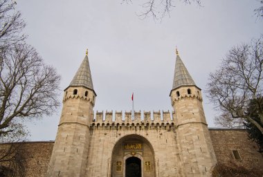 İki kuleye sahip bir duvar ve ortasında giriş kapısının üzerinde birkaç siper var..