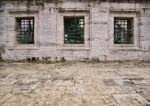 Paving stones and lattice windows in a stone wall in front of a cemetery in Istanbul